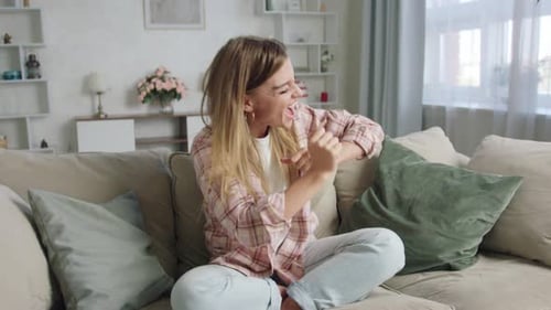 Cheerful Woman Dancing on Couch in Bright Living Room