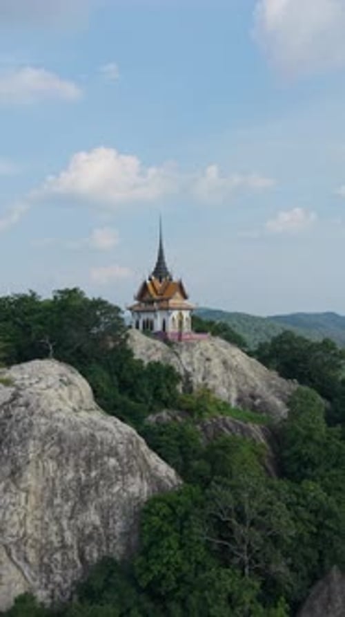 Petit temple bouddhiste au sommet d'une montagne rocheuse parmi les arbres de Thaïlande