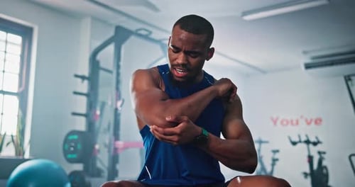 Elbow pain, fitness and injury with black man in gym for accident, cramp or muscle fatigue