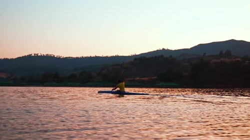 Kayaker Paddling on Calm Lake at Sunset