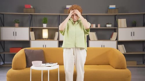 Woman Massaging Head on Couch Indoors