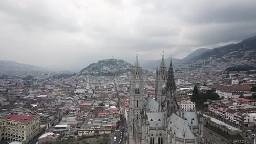 Cinematic drone orbiting shot of gothic Basilica del Voto Nacional in Quito with cityscape on hill i