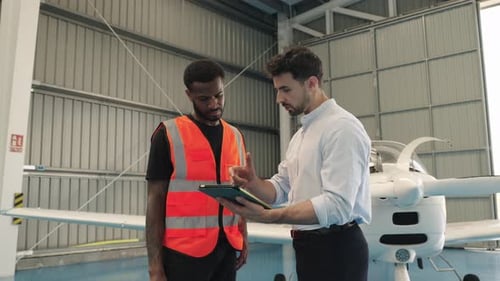 Aircraft Maintenance Crew Reviewing Flight Plans on Tablet in Hangar