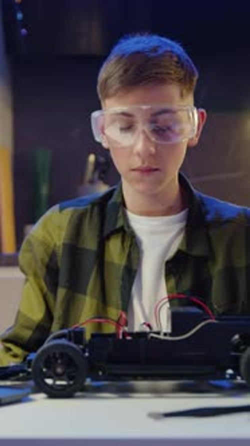 Teenage Boy Repairs a Toy Car in Workshop