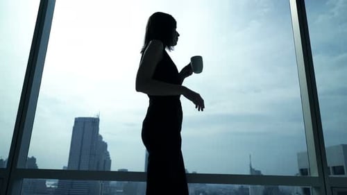 Silhouette of Businesswoman Drinking Coffee and Admire View From Window in Office 30s