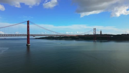 Pont suspendu rouge sur le Tage scintillant avec une scène animée au bord de l'eau