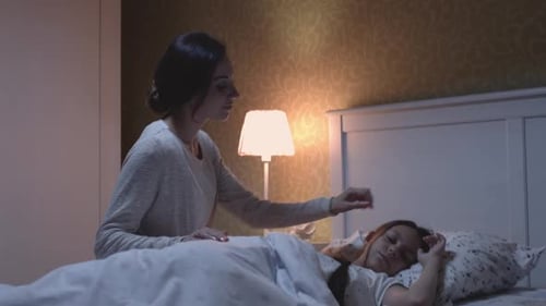 Woman puts child to sleep in cozy bedroom