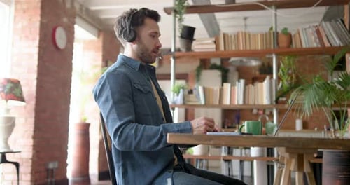 Man with Headset Working Remotely on Laptop