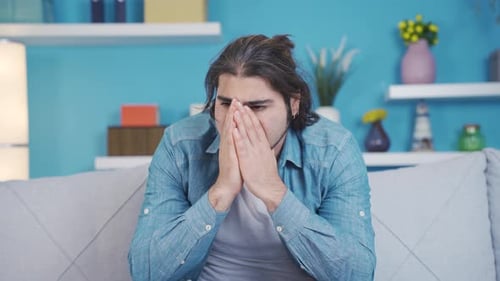 Distraught Man Sits on Couch in Home