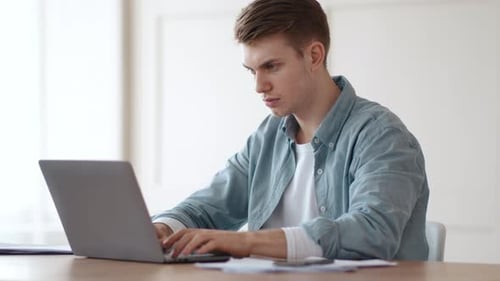 Young Concentrated Guy Typing on Laptop at Home Office