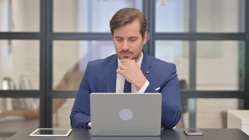 Man Wearing Suit Working at Laptop in Office