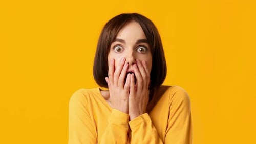 Shocked Woman Looks Scared on Yellow Background