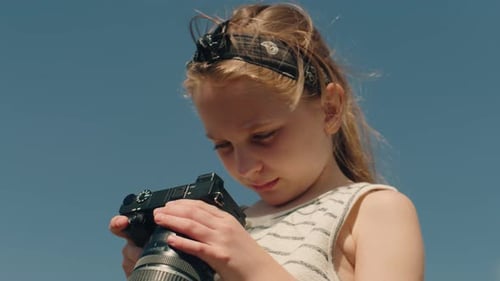 Girl Holding a Camera Outside Under a Blue Sky