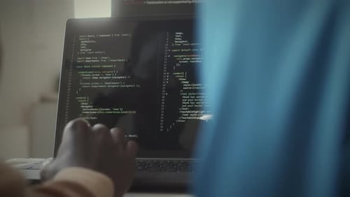 Programmer Coding on Laptop and Talking with Coworker