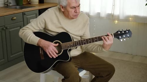 Senior Man Plays Guitar in Bright Room