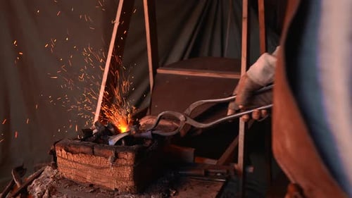 Hard work with iron. Media. A man on the street in a hat is working with fire and iron.