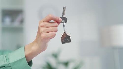 Person Holding Up Key With House Keychain