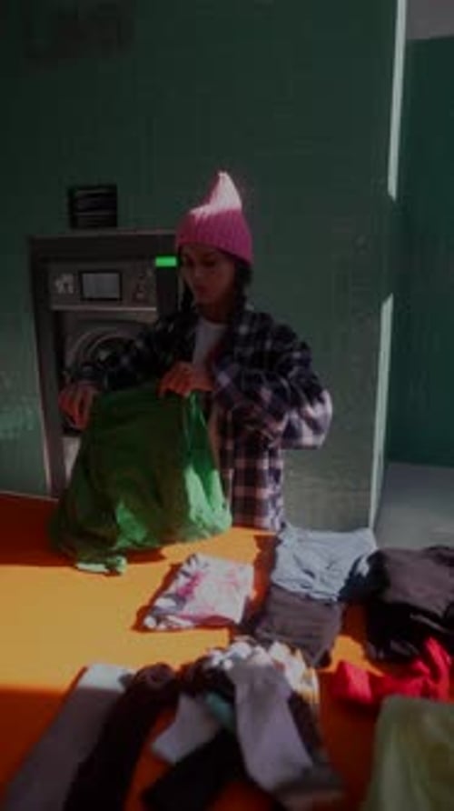 Young Adult Folds Laundry at the Laundromat