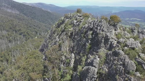 Aerial flight to shattered and rugged rock wall of Sugarloaf peak, AUS