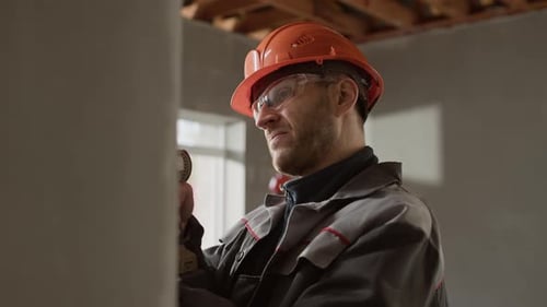 Construction Worker Using Drill at Building Site
