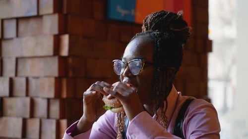 African American Woman Enjoying a Burger in Fast Food Restaurant