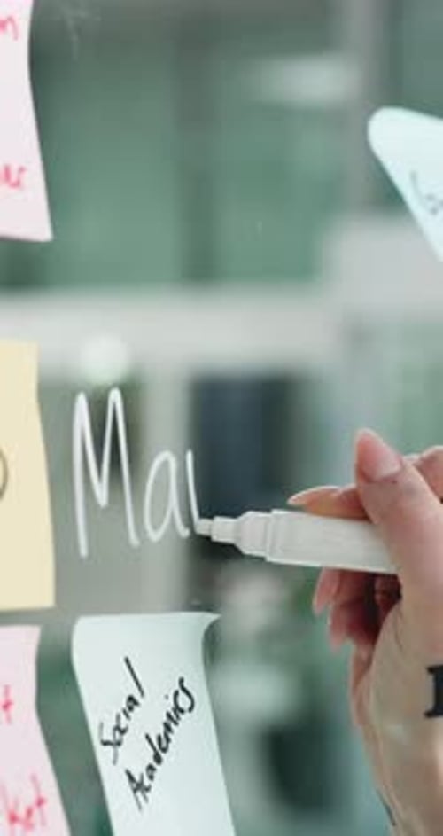 Woman Writes Marketing on Glass Board in Office