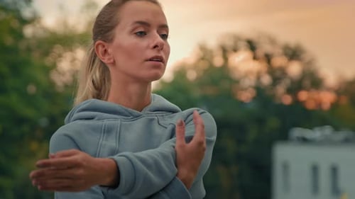 Woman Stretching Arms Outdoors at Sunrise