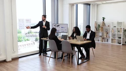Business Man Giving Presentation to Multiracial Colleagues in Modern Office