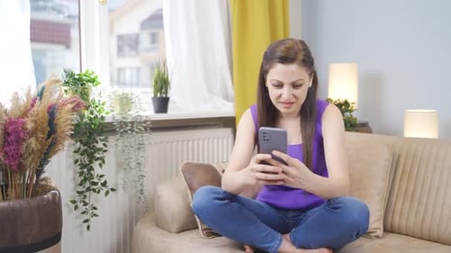 Woman Using Cell Phone on Couch Reacts