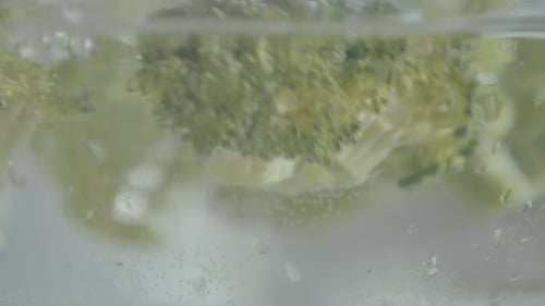 detail of a broccoli falling into the water in slow motion, natural light