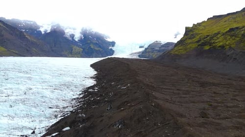 Aerial view of melting glacier in the icelandic mountains, in a rocky valley. (climate change)