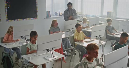 Elementary School Children Using Computers Doing Creative 3D Design Projects Teacher Helping Boys