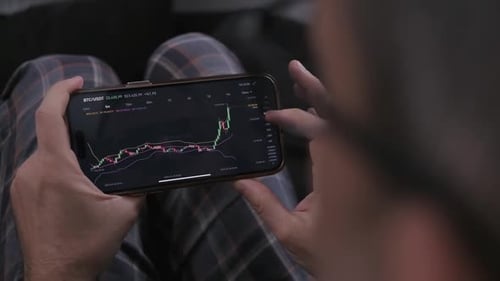 Caucasian Man at Home Trade and Earn Money on the Cryptocurrency Exchange Online Using His Phone