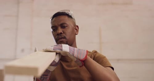 Man Inspecting Wood Plank Wearing Safety Glasses