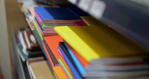 Closeup of Stack of Multicolored Notebooks and Exercise Books on Shelf in Shop