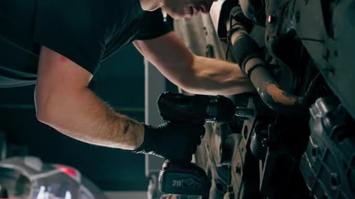Vertical Video Close Up an Auto Mechanic at Service Station Checks a Car Being Lifted on a Lift