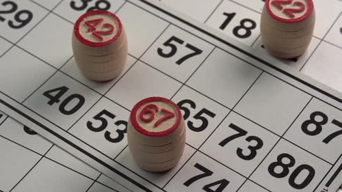 Lotto cards with numbers board game wooden barrels close up rotate background low light. Bingo