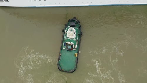 Tug boat assisting cruise ship arrival to port. Bottom sediment mixed by vessel propulsion. Ascendin