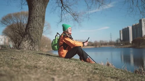 Old Woman Sitting on Coast of Pond in City Park Rest After Workout Active Life Cute Grandmother