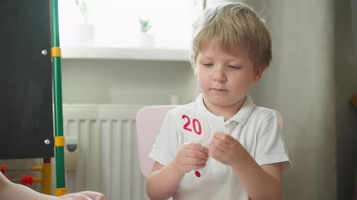 Young Boy Counting with Number Cards at Home