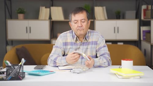 Man Counts Money at Table Indoors