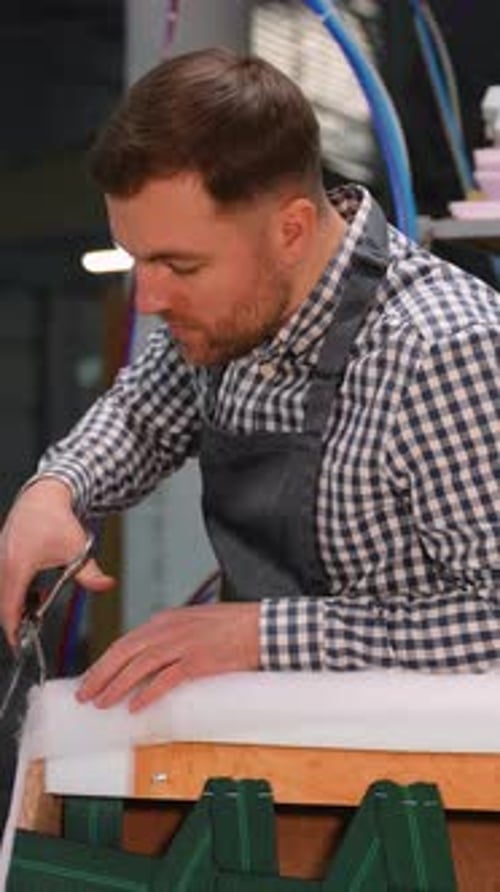 Craftsman Carefully Cutting White Material in Workshop