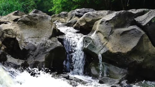 Water stream glides over rockson the forest. Close up shot of a cascade in the woods - SLOW MOTION,
