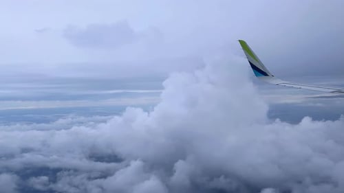 Vue d'une aile d'avion volant à travers les nuages au cours d'un voyage serein en altitude.