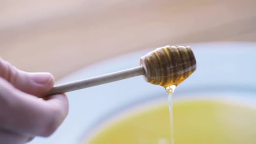 Honey Dipper with Dripping Honey Over a Bowl