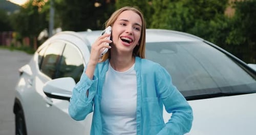 Cheerful Woman Talking on Phone Beside Car