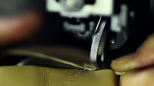 Leatherworker hand stitching leather in action at a handmade tailoring design studio