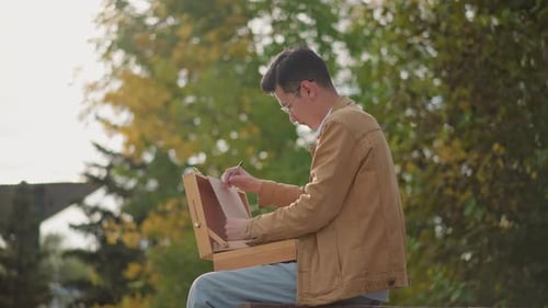 Young Man Drawing in Park on Sunny Day