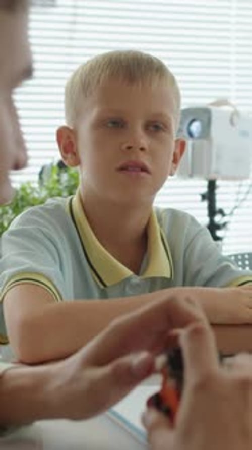 Schoolboy Listening to Tutor Holding Small Robot at Engineering Class