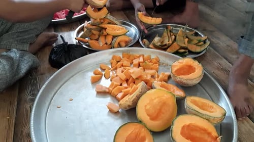 Mains d'un homme âgé utilisant deux couteaux pour couper du cantaloup frais et délicieux et du melon musqué dans de grandes assiettes, A